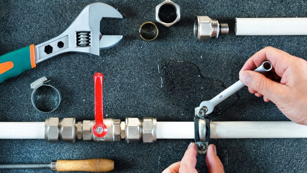 Plumber repairing a pipe valve with an adjustable wrench in Soledad