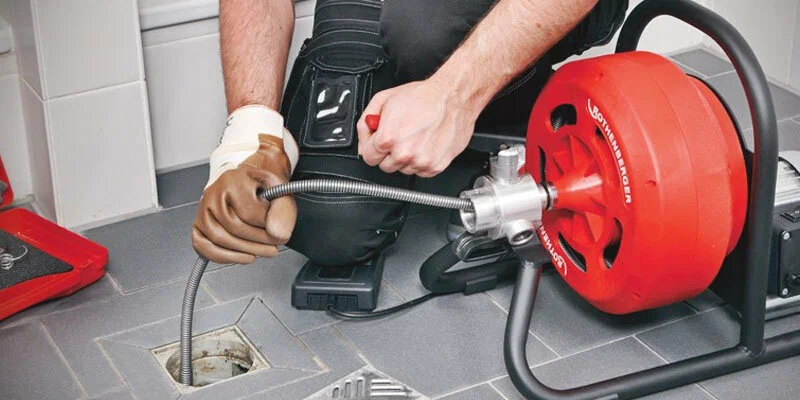 Plumber using a drain-cleaning machine in Soledad